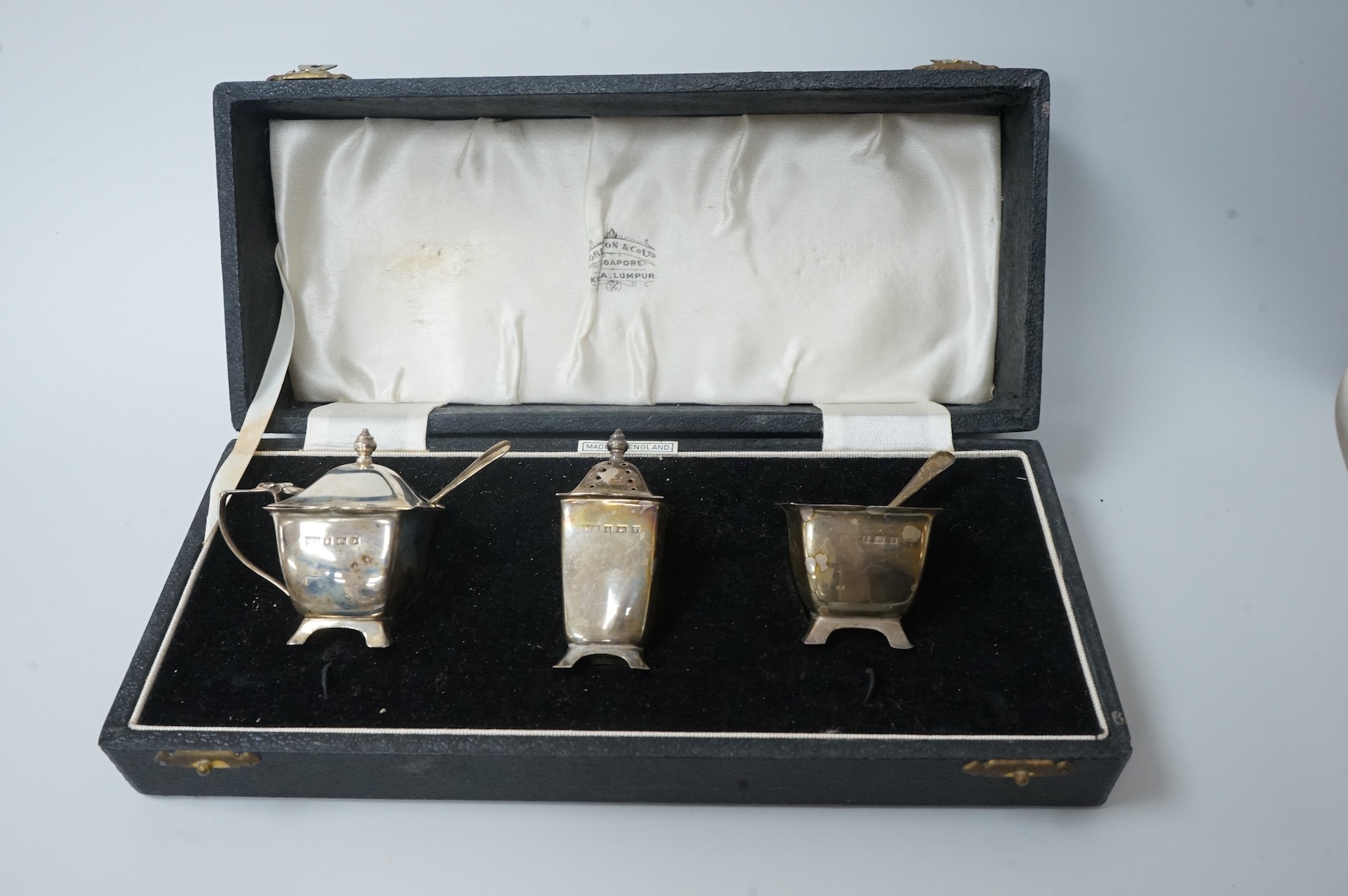 A pair of cased Elizabeth II silver three piece condiment sets, by William Adams Ltd, Birmingham, 1955, one spoon missing.